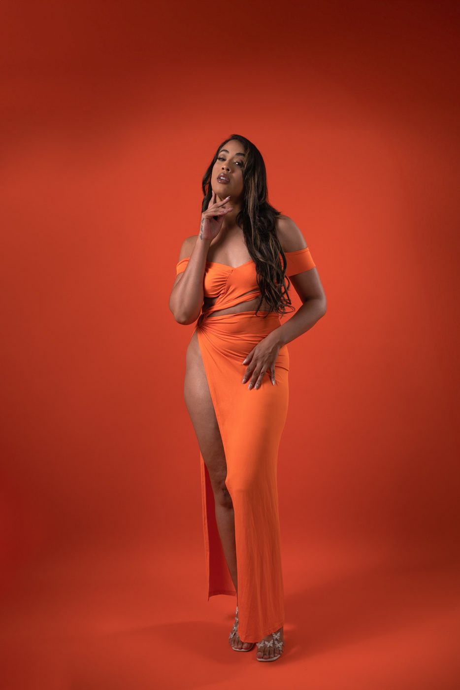Editorial portrait in an orange gown on a red backdrop