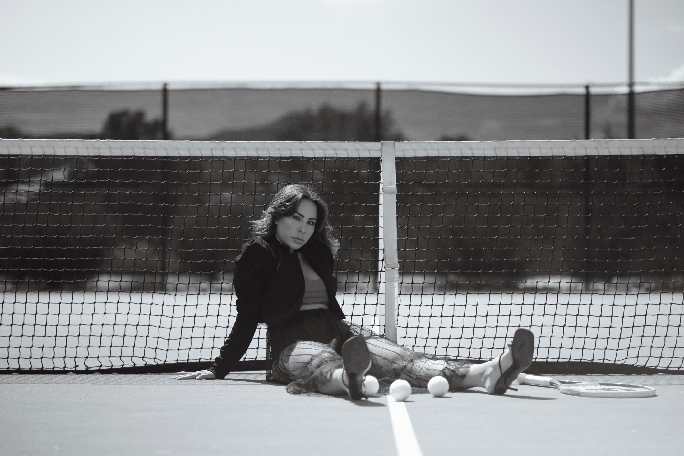 Editorial portrait seated against a tennis net