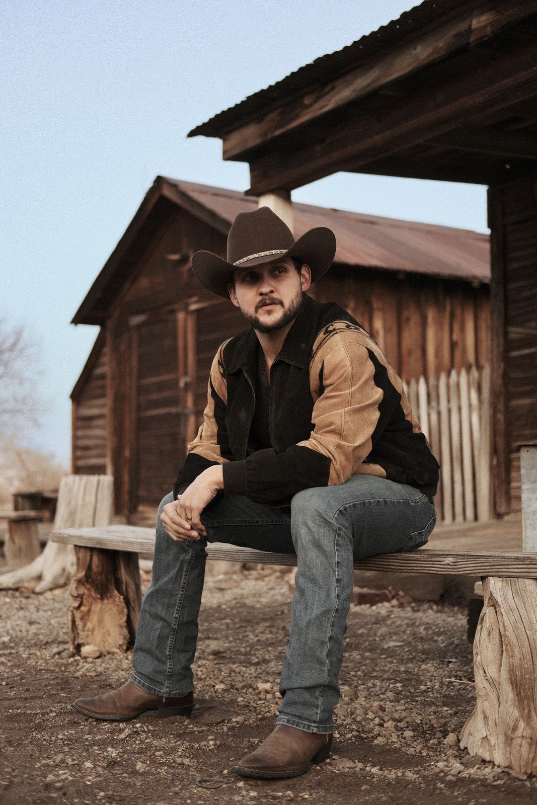 Lifestyle portrait seated outside a ranch barn