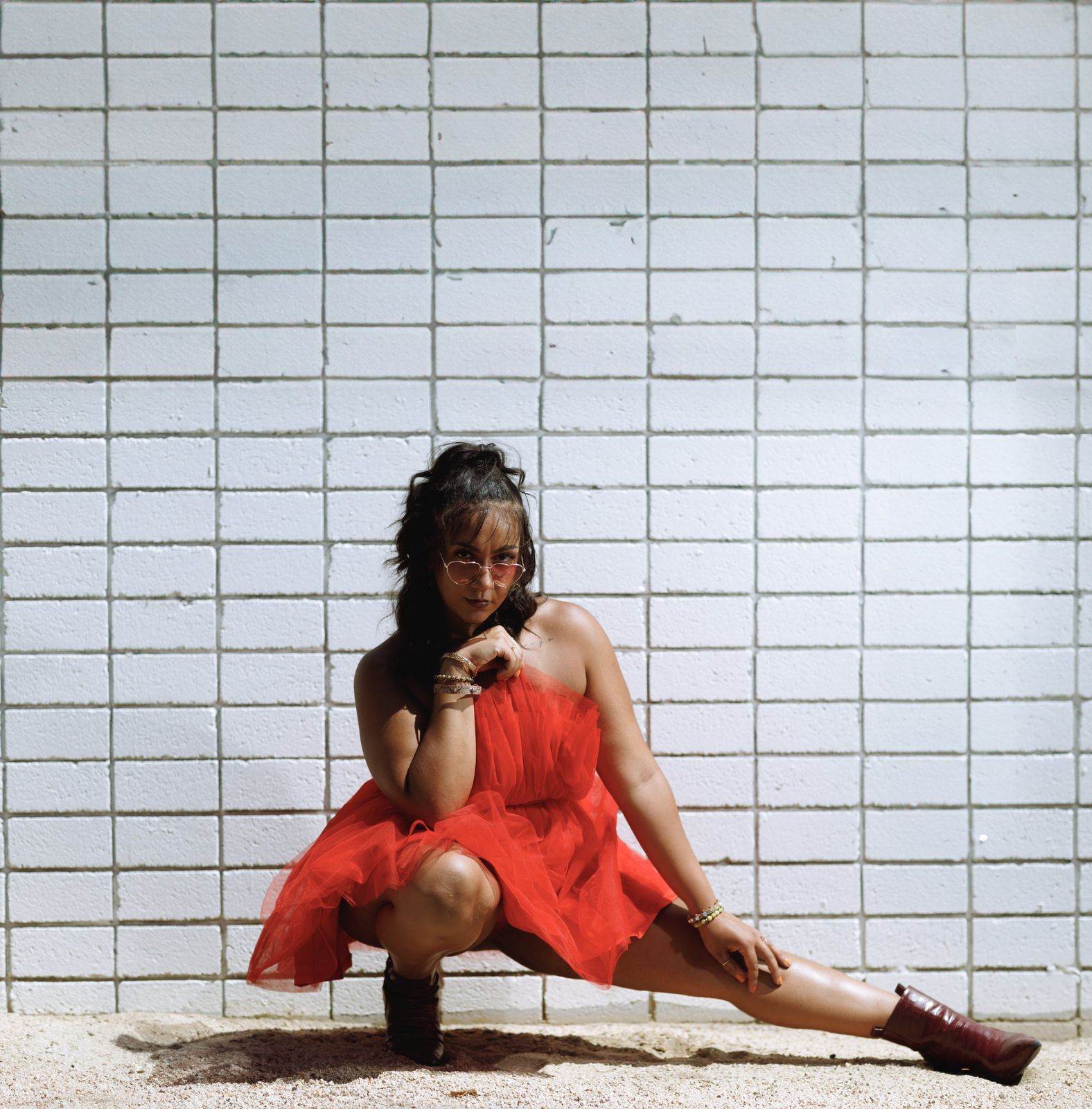 Lifestyle portrait crouched against a white brick wall