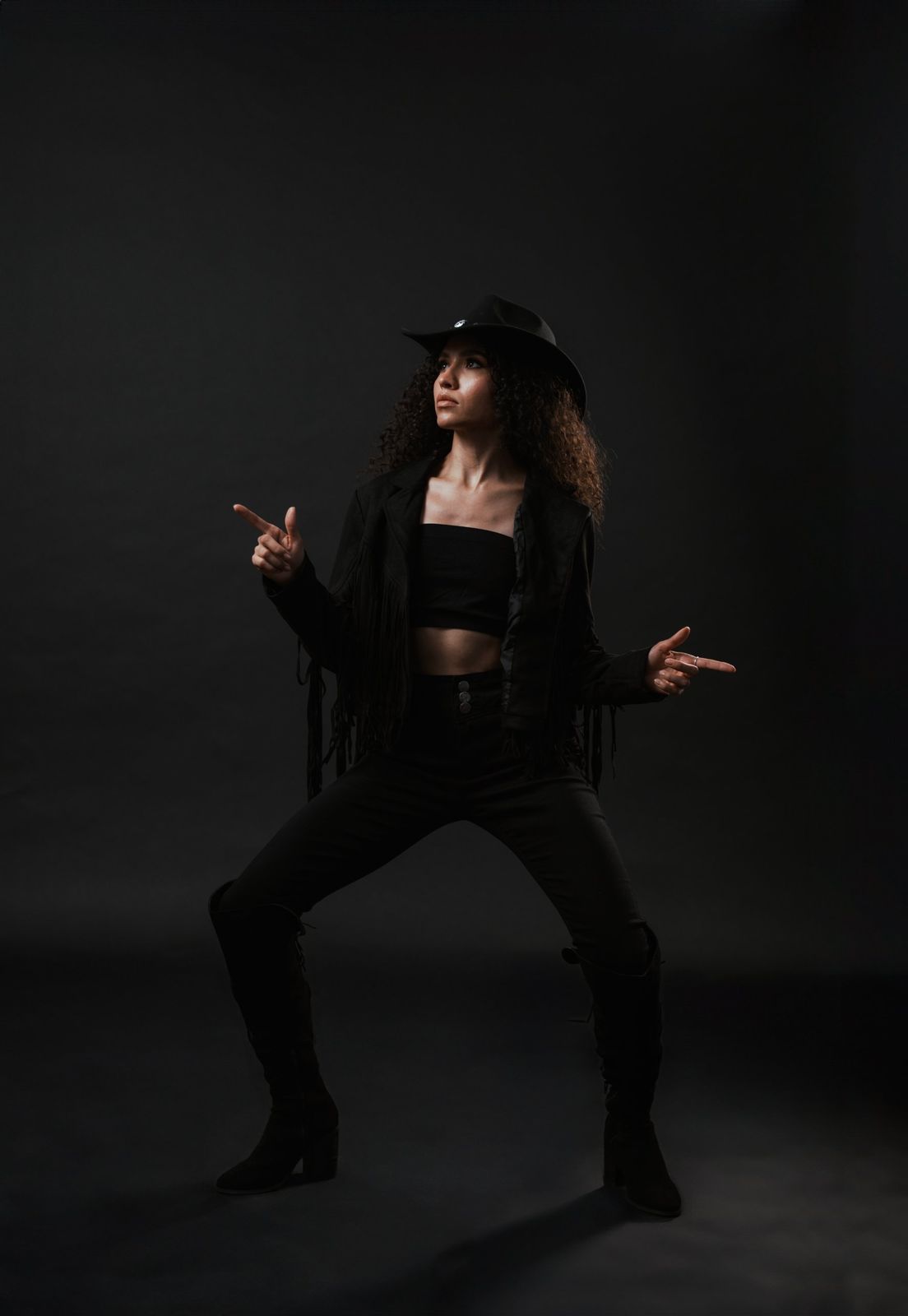 Editorial portrait in a fringe jacket and wide-brim hat